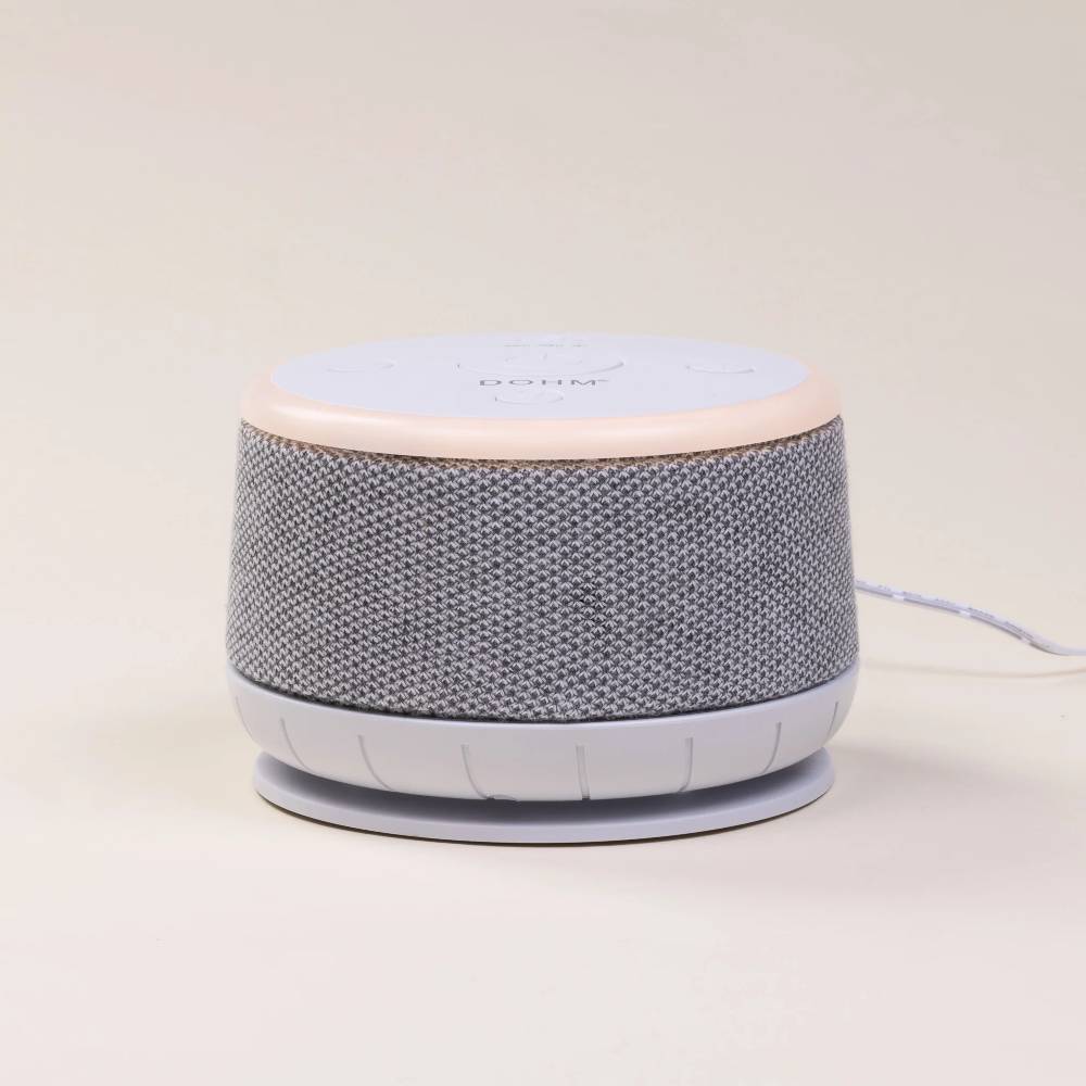Dohm Nova white noise machine with textured gray body and white top on a light beige background
