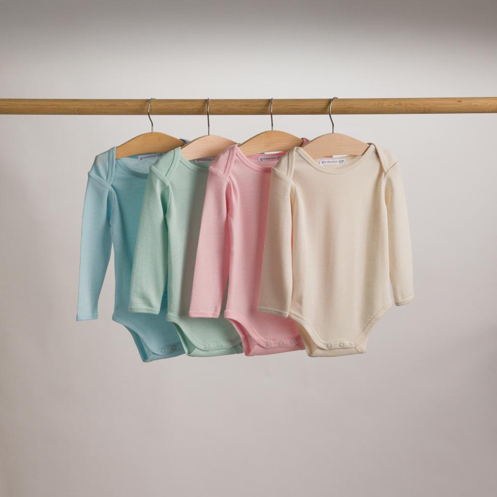 Four pastel-colored baby merino bodysuits hanging on a rack against a neutral background