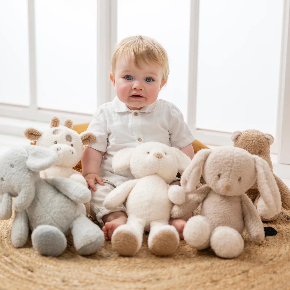 Baby surrounded by plush toys in a soft, indoor setting