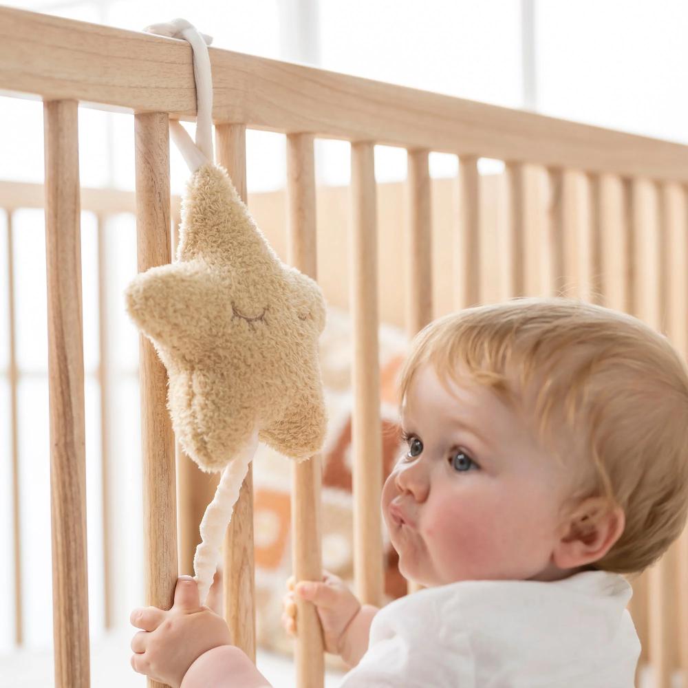 Baby looking at a star-shaped musical mobile in a crib