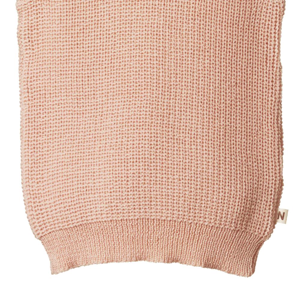 Close-up of a pink knitted merino wool sweater vest with a Nature Baby brand label on a white background