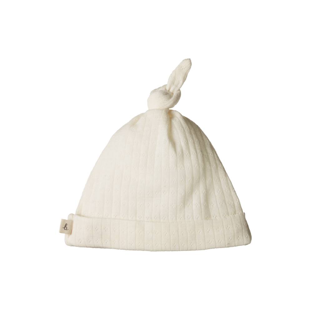Cream baby hat with a knot on top against a white background