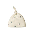 Cream-colored pointelle fabric baby hat with purple berry patterns on a white background