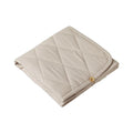 Folded beige quilted change mat with a bamboo button on a white background