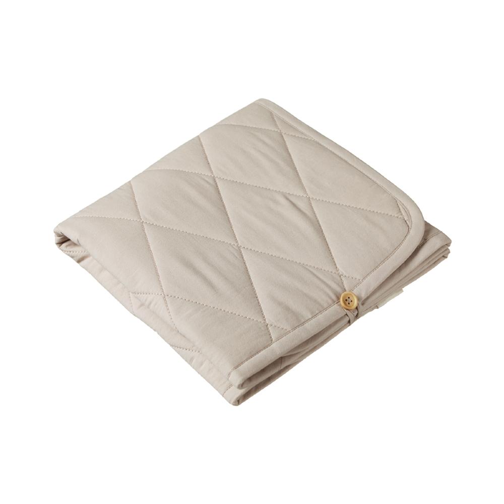 Folded beige quilted change mat with a bamboo button on a white background