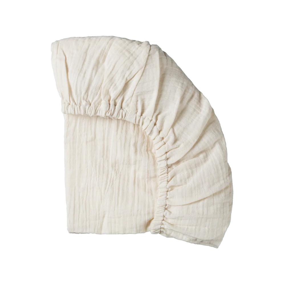Cream organic cotton muslin fitted sheet on a white background