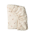 An off-white organic cotton fitted sheet with a delicate red and brown goose pattern, shown folded on a solid white background.
