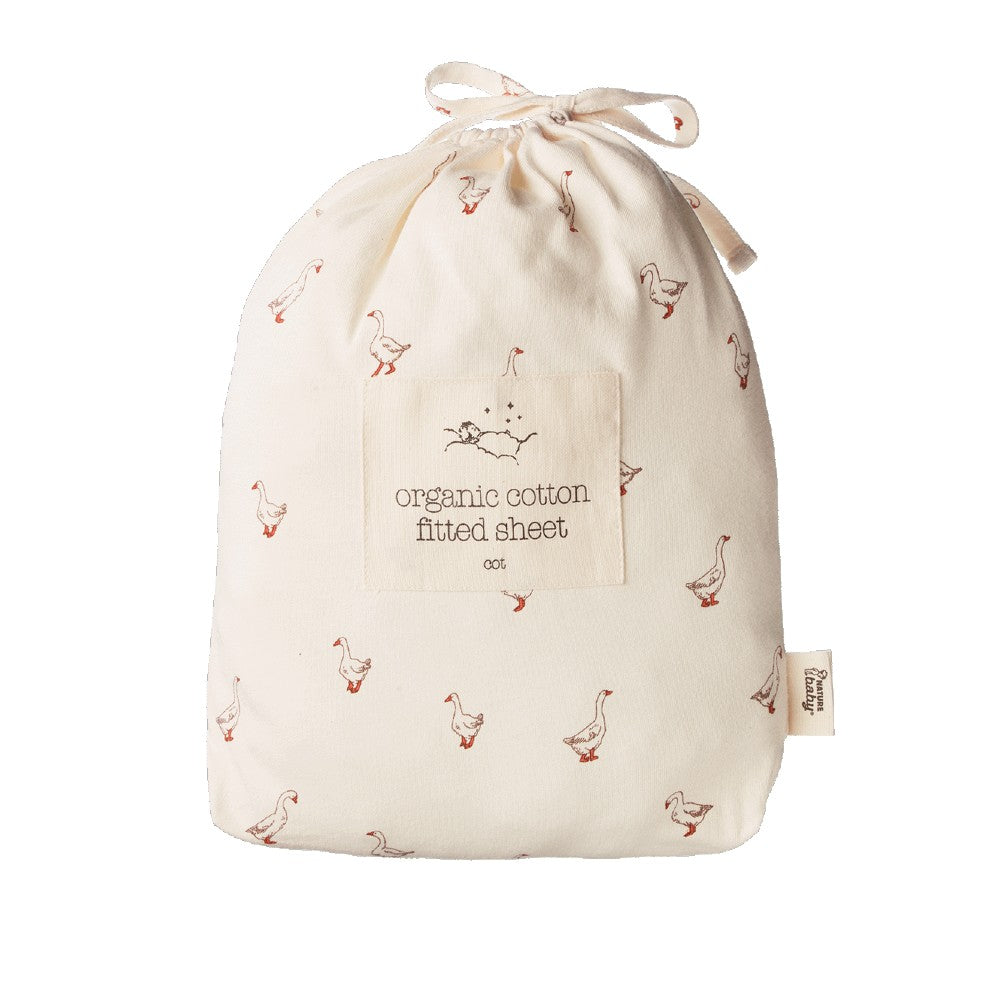 An organic cotton fitted sheet packaging bag in an off-white color, printed with small brown and red geese. It is gathered into a drawstring bag with a fabric label in the center that reads 'organic cotton fitted sheet' and a small side tag.