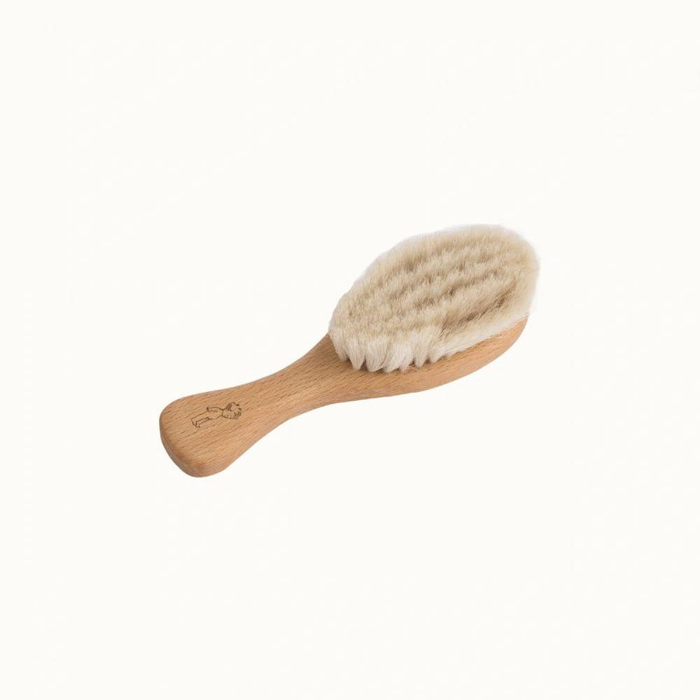 Beige wooden baby brush with natural goat bristles on a white background