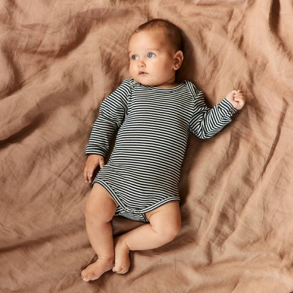 Baby in a navy and white striped bodysuit onesie lying on a brown textured blanket