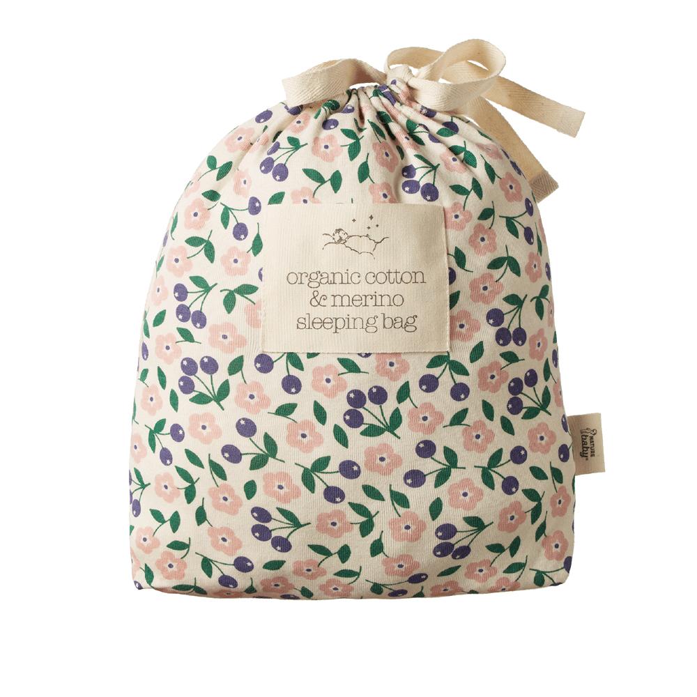Floral-patterned organic cotton and merino sleeping bag outer package with a drawstring on a white background