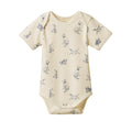cream cotton baby bodysuit with short sleeves and envelope neck with blue dog pattern on a white background