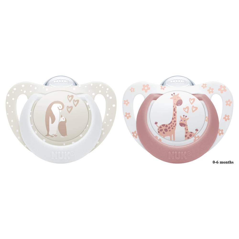 Two NUK baby pacifiers on a white background, one with a penguin design in beige and white, and the other with a giraffe design in pink and white. The text '0-6 months' is printed on the right pacifier.