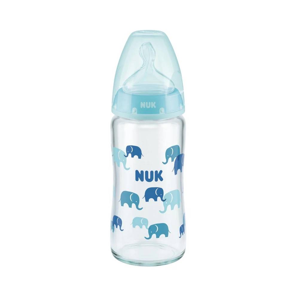 A NUK baby bottle with a clear glass body decorated with blue and light blue elephant patterns and the name 'NUK' printed in blue. It features a light blue collar and a translucent light blue silicone nipple on a solid white background.