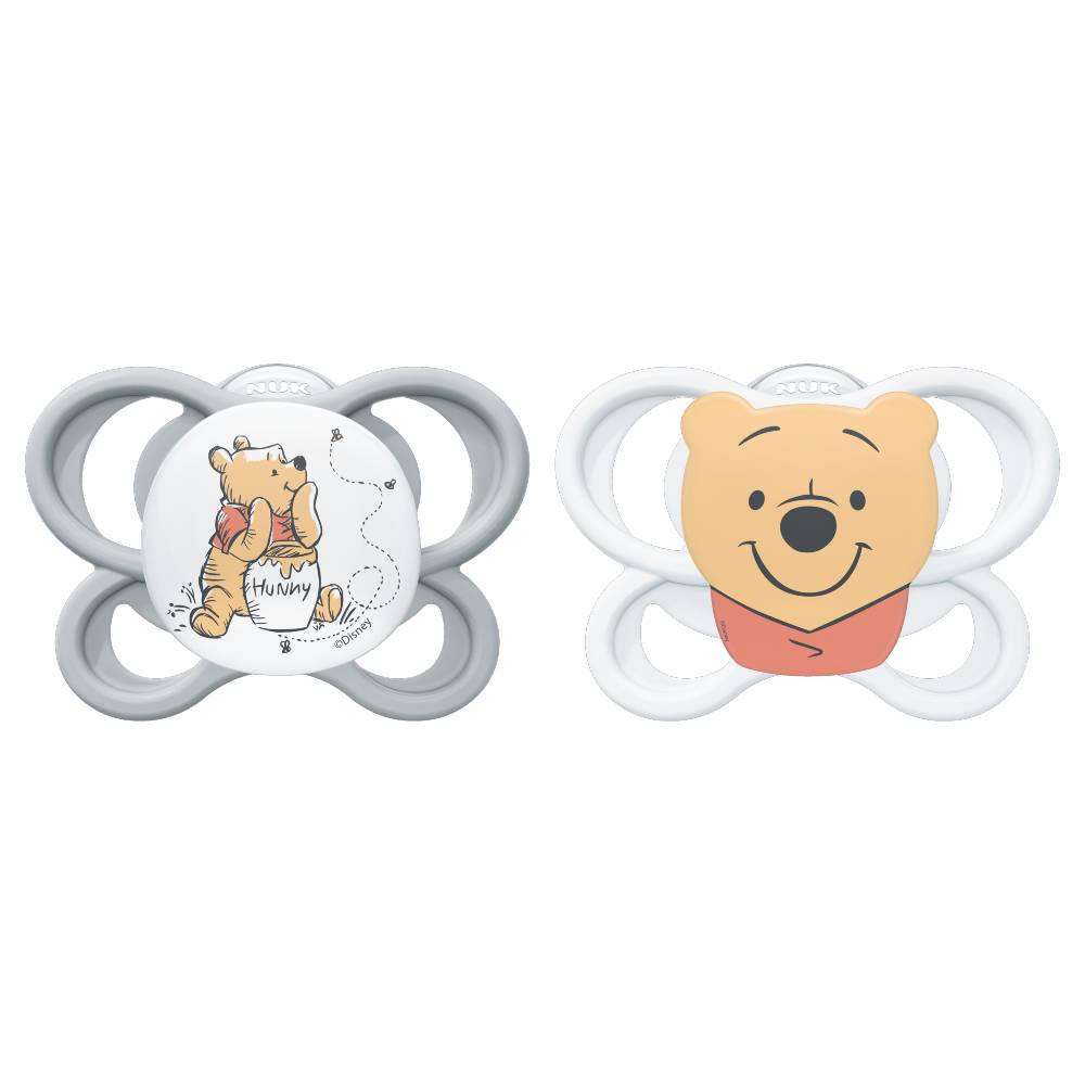 Two Winnie the Pooh baby pacifiers on a white background, one with a gray shield and a white center featuring Pooh, and the other with a white shield and a white center featuring Pooh's face.