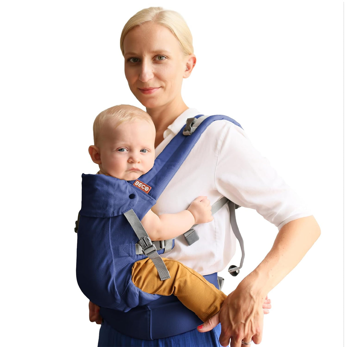 Woman holding a baby in a navy Beco Gemini baby carrier against a white background