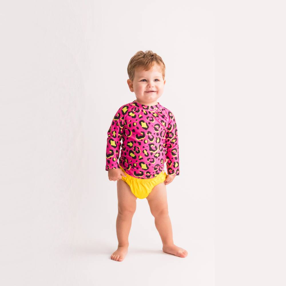 Child wearing a pink leopard print swim rash vest and yellow swim nappy on a white background