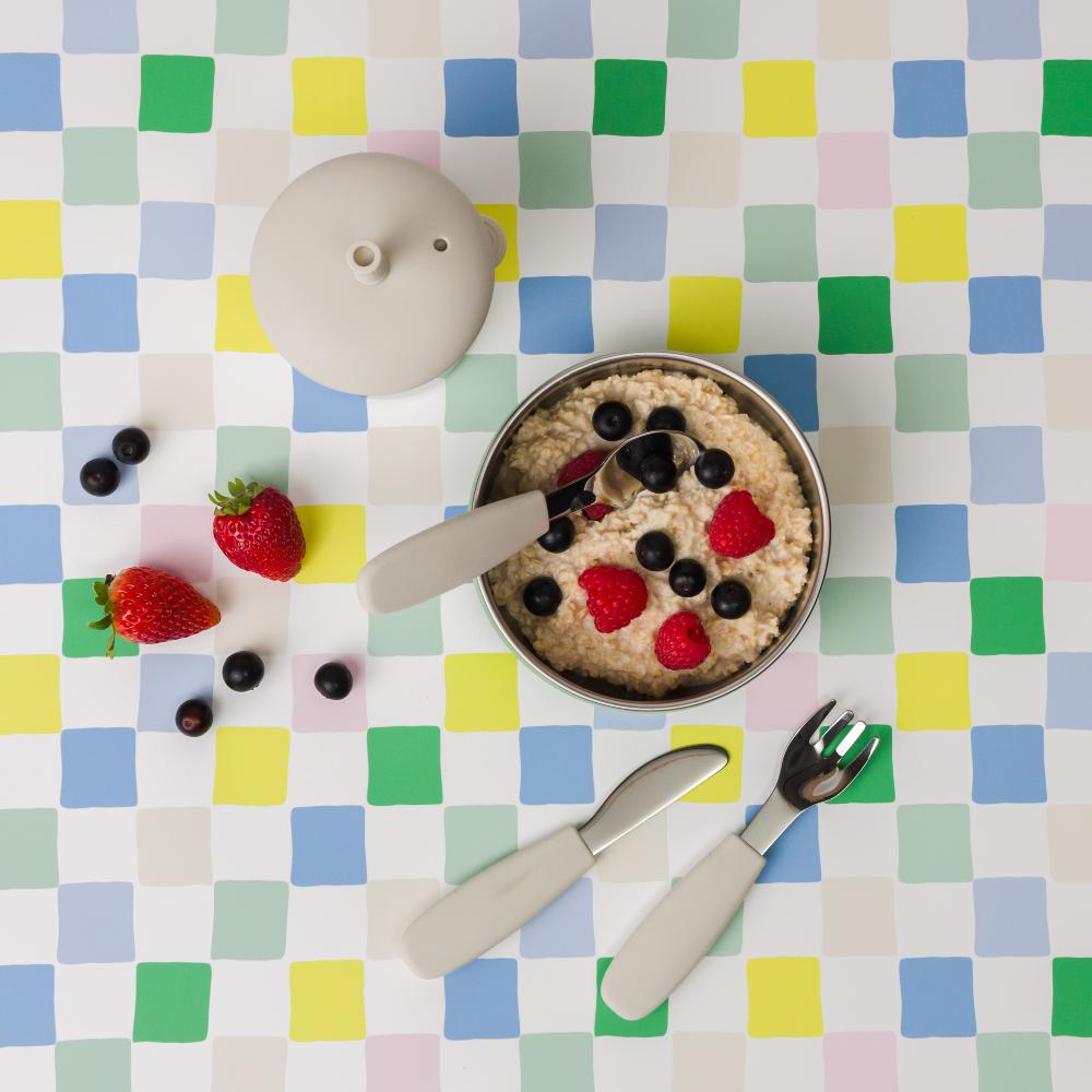 Bowl of oatmeal with berries on a colorful checkered tablecloth with Nestling stainless steel cutlery