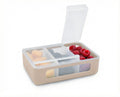 Beige bento box with compartments containing fruits and vegetables on a white background