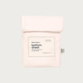 A pale pink folded cotton bottom sheet in its branded paper sleeve packaging, shown against a solid light gray background. The packaging features a white rectangular label with black text reading 'bubu basics.