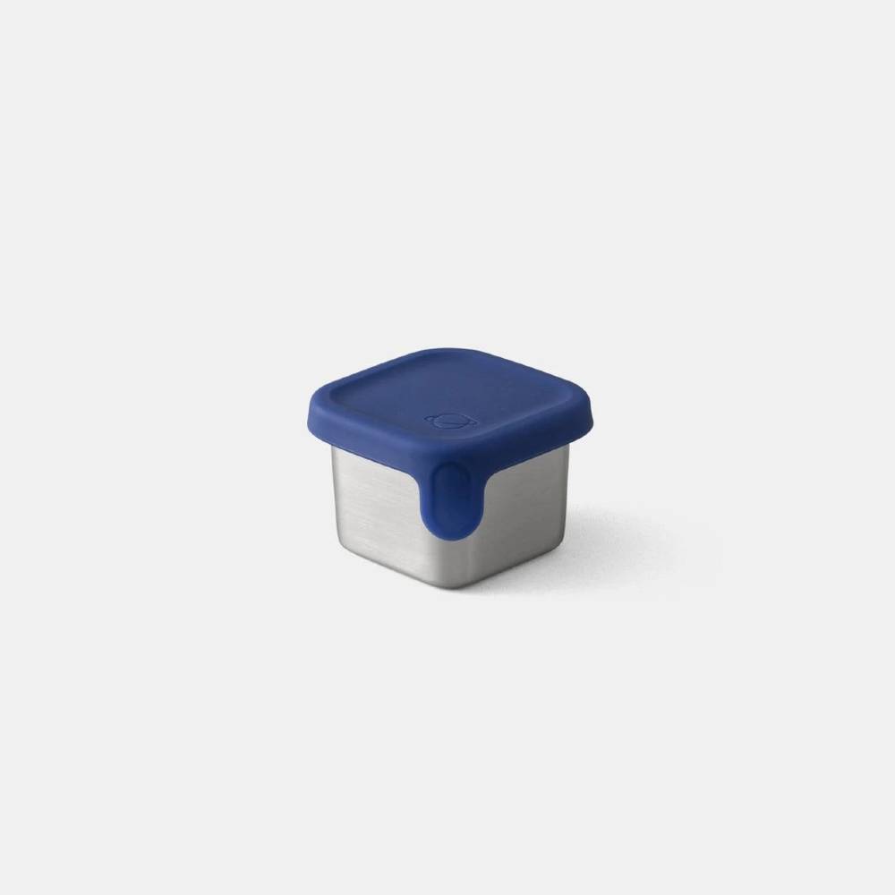 A square stainless steel food storage container with a dark blue silicone lid and matching blue spill-resistant tab, shown on a light gray background.