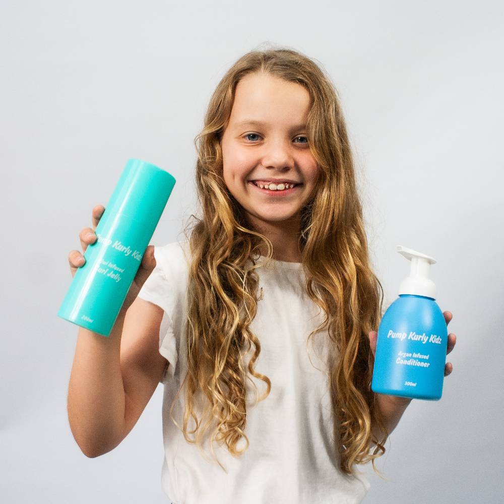 Child holding pump haircare bottles against white background.