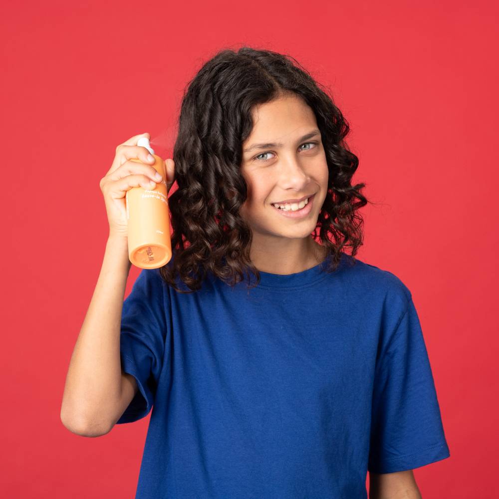 Child holding Pump Haircare bottle against red background.