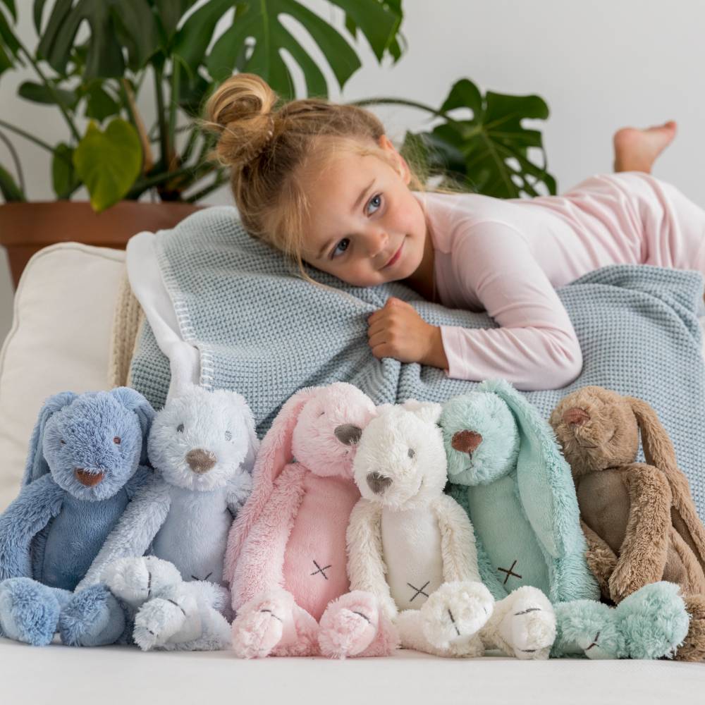 Child lying on a couch with plush toys in front