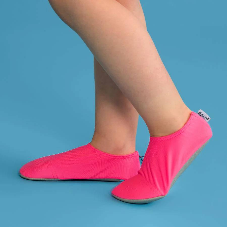 Pink slipfree water shoes worn by a person on a blue background
