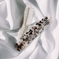 Seasons Of Mama birth combs against white fabric background.