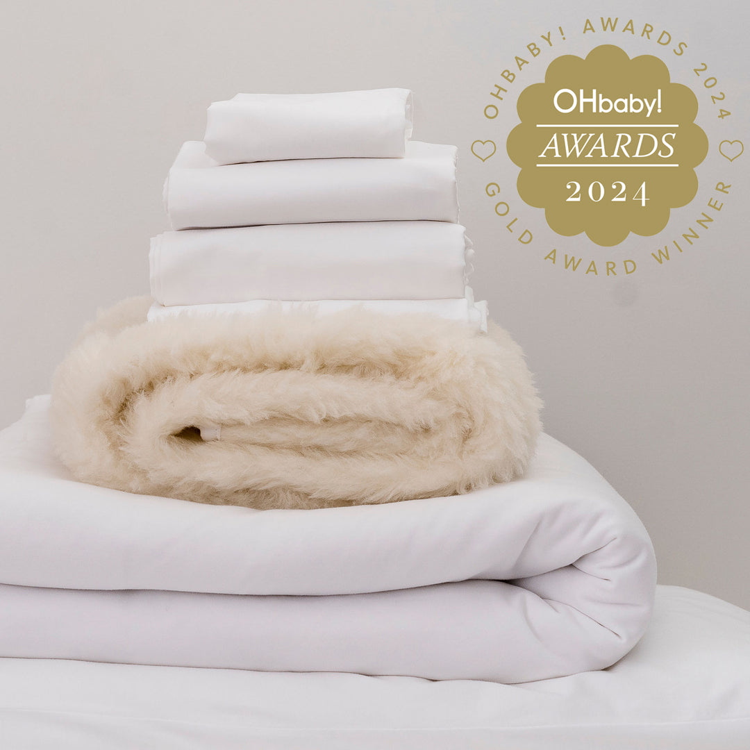 Stack of white towels with a beige blanket on a light gray background, featuring the OHbaby! Awards 2024 logo.