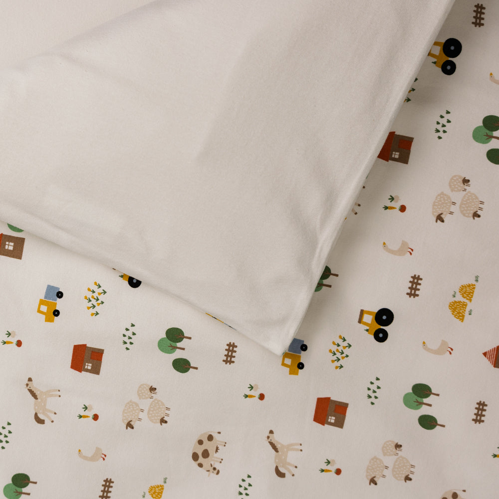 Organic Cotton Cot Duvet Cover - Transport with a white pillowcase on a bed. 