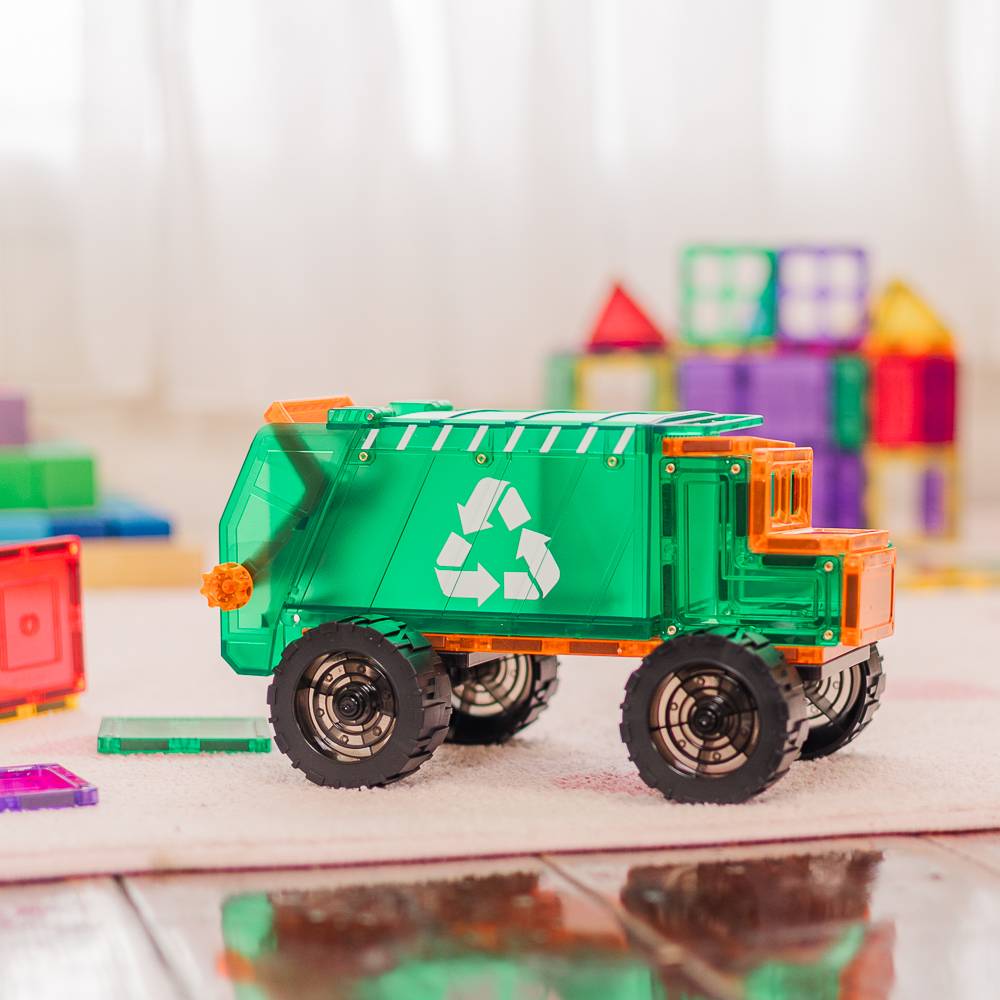 Toy garbage truck with recycling symbol on a reflective surface, colorful tiles in the background
