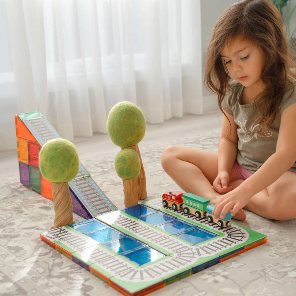 A young girl playing with Tile Tek and Tile Tek Toppers as a train set. 