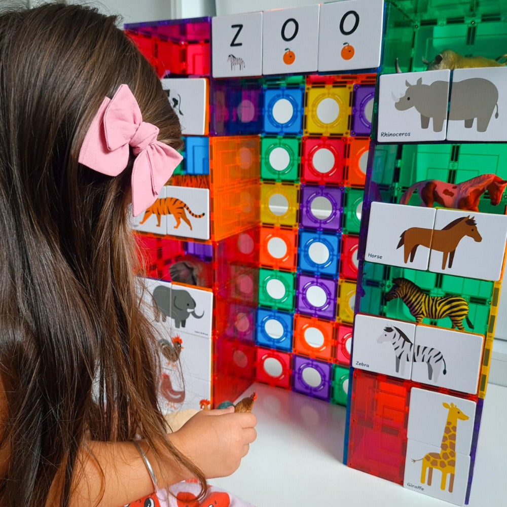 A girl playing with Tile Tek Toppers and Toy Animals. 