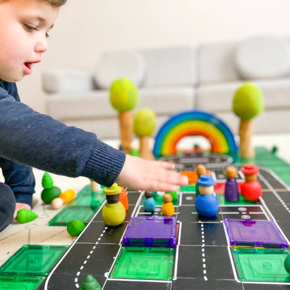 A young boy playing with tile tek and tile tek road pack toppers. 