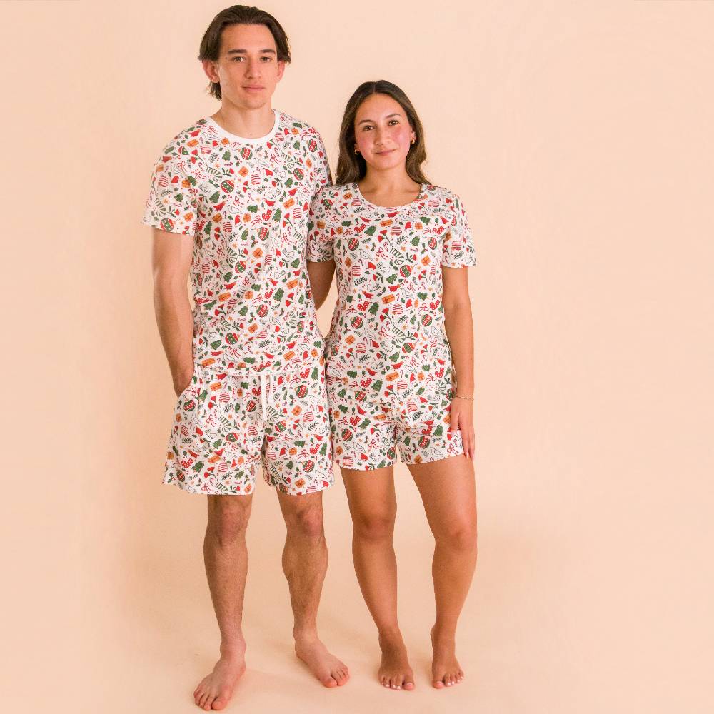 Two people wearing matching christmas pattern short sleeve pajama set on a beige background