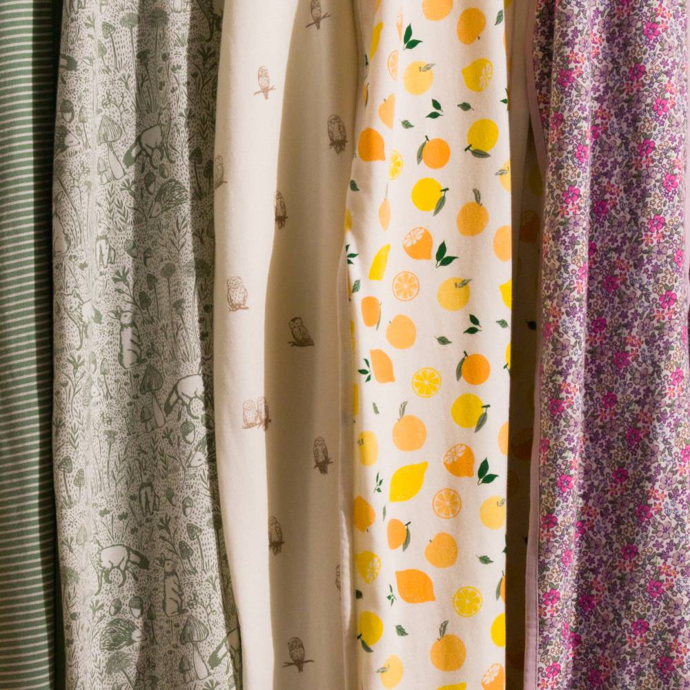 Organic Cotton collection of patterned Sleep Sacks including floral, citrus, and nature-themed designs.