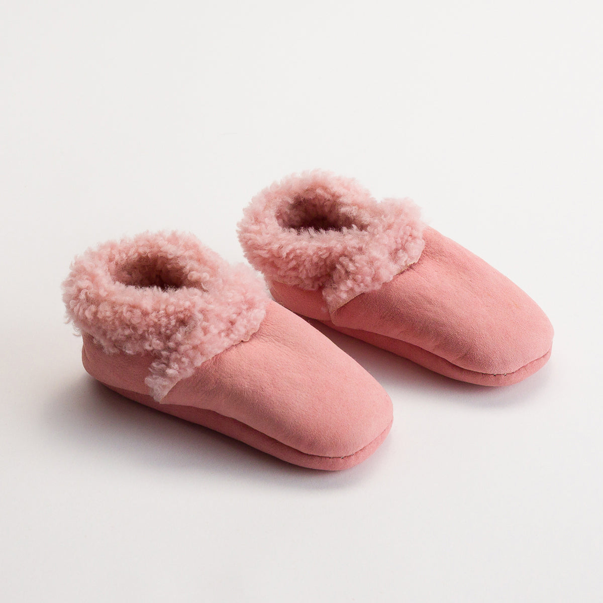 Pair of pink slippers with fluffy trim on a light background