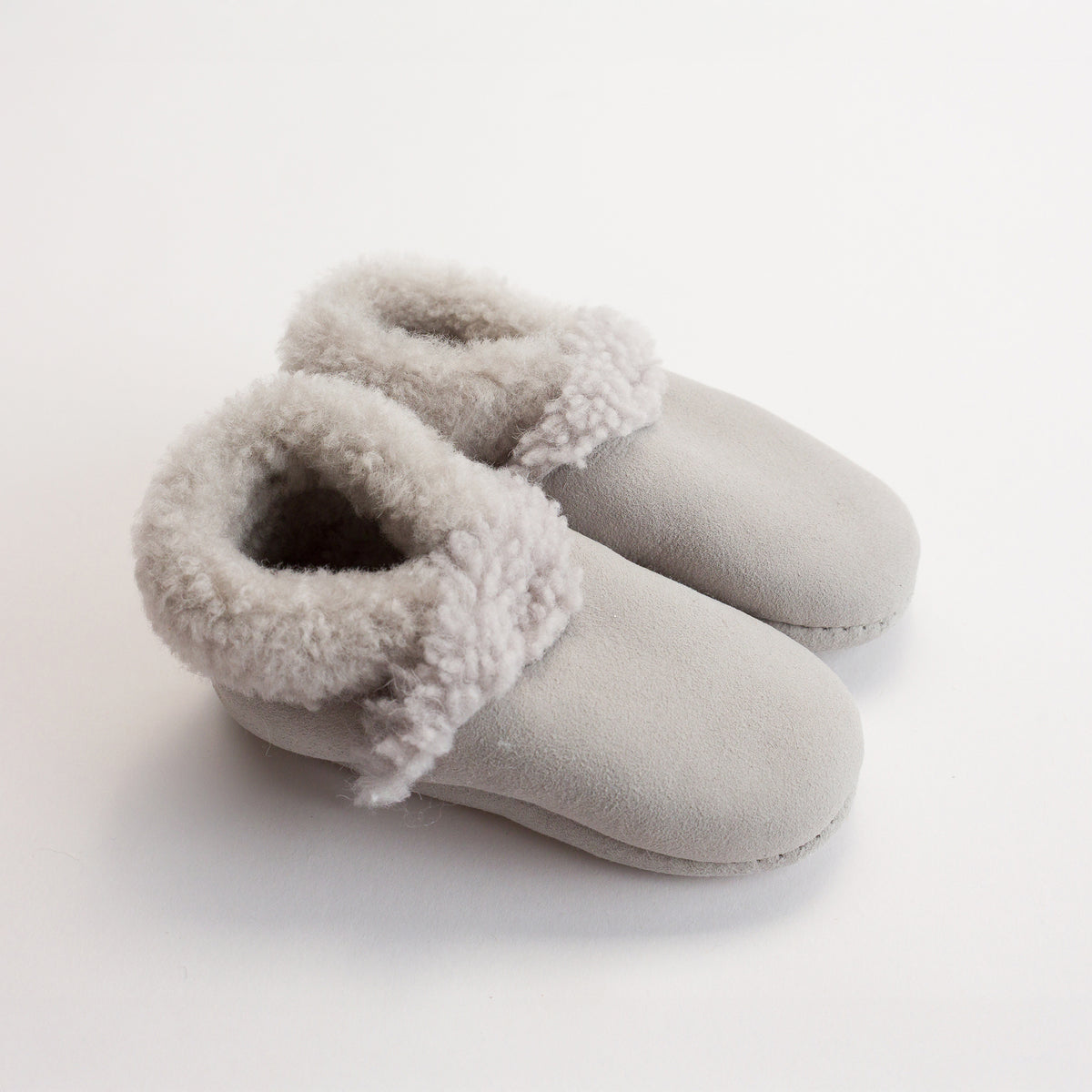 Pair of gray woolbabe lambskin baby booties on a white background