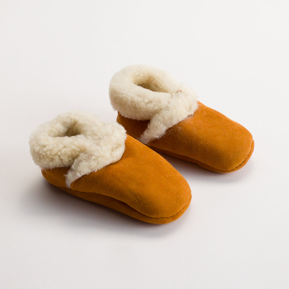 Pair of brown wool children's slippers with white fur trim on a light background