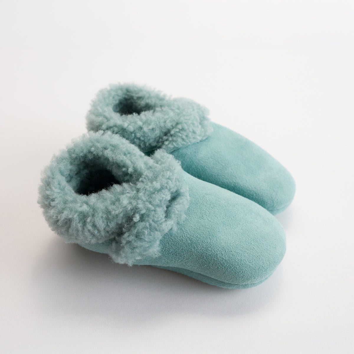 Pair of light blue lambskin booties on a white background