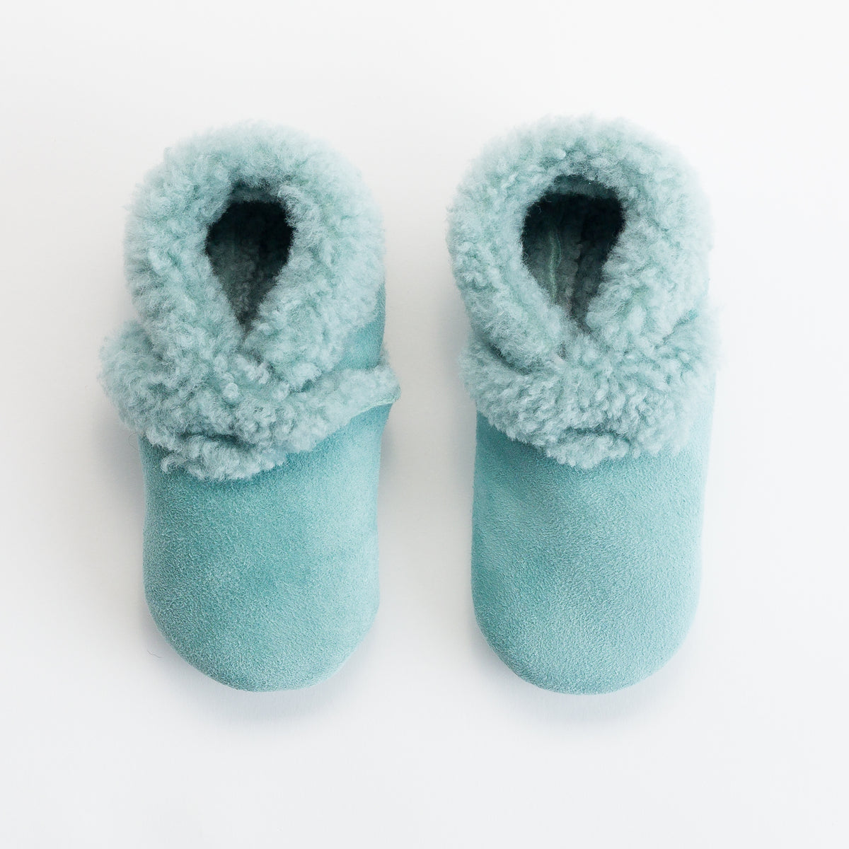 Pair of light blue fuzzy slippers on a white background