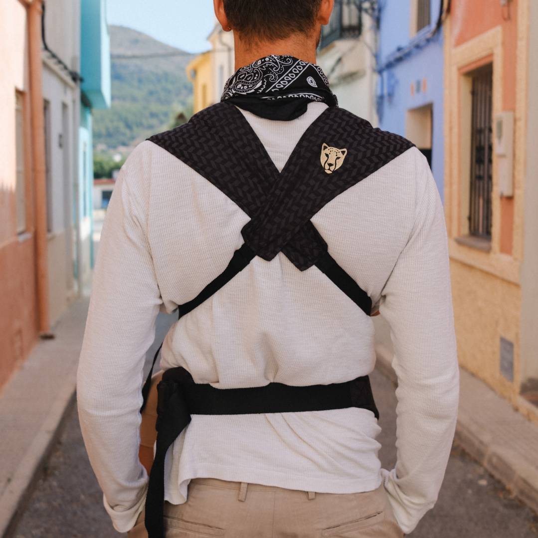 A back shot showing a black baby carrier straps crossed on the back. 