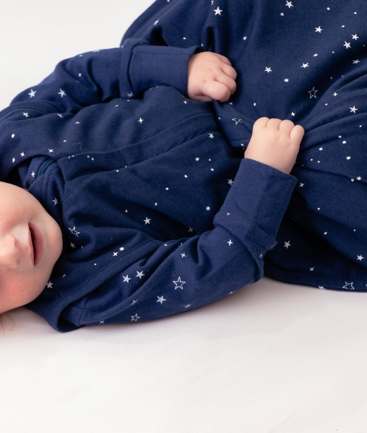 Baby wearing a navy blue outfit with star patterns on a white background