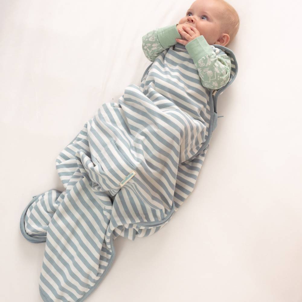 Baby in a blue and white striped woolbabe sleeping bag on a white background