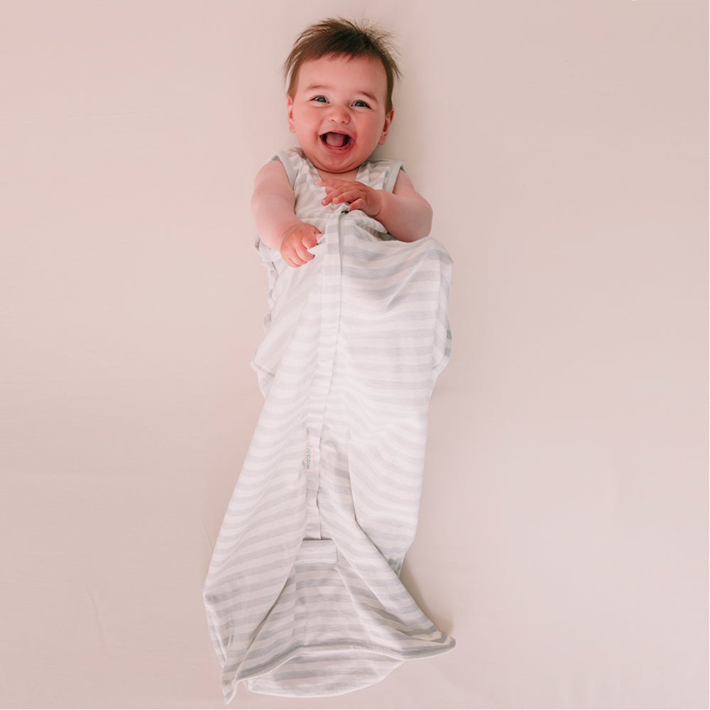 Baby wrapped in agrey stripe woolbabe summer sleep sack on a plain background