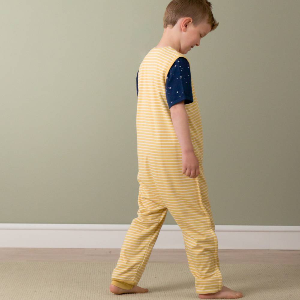 Child wearing a yellow striped onesie with navy sleeves against a plain wall.