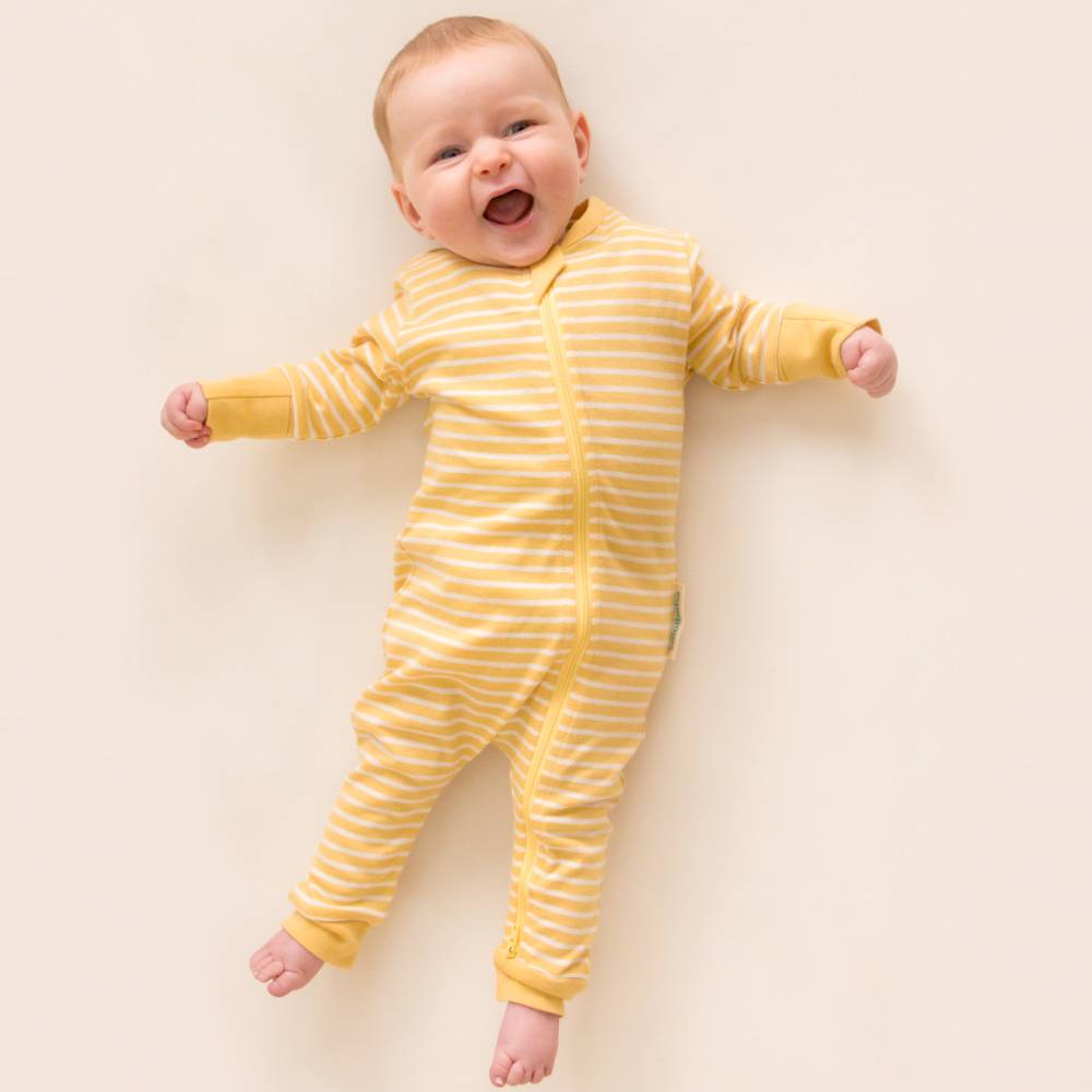 Baby wearing a yellow and white striped woolbabe PJ Suit onesie on a beige background