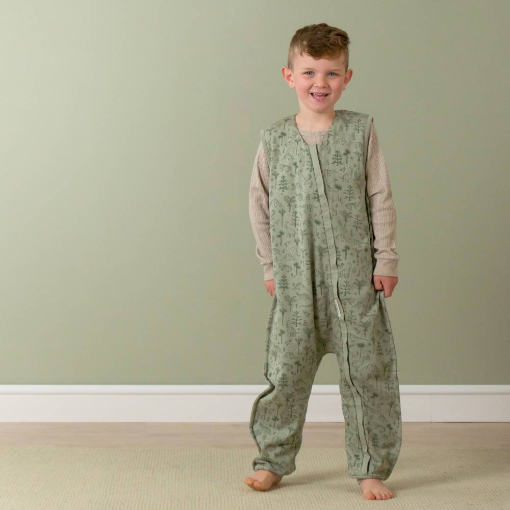 Child wearing a green patterned onesie against a plain background